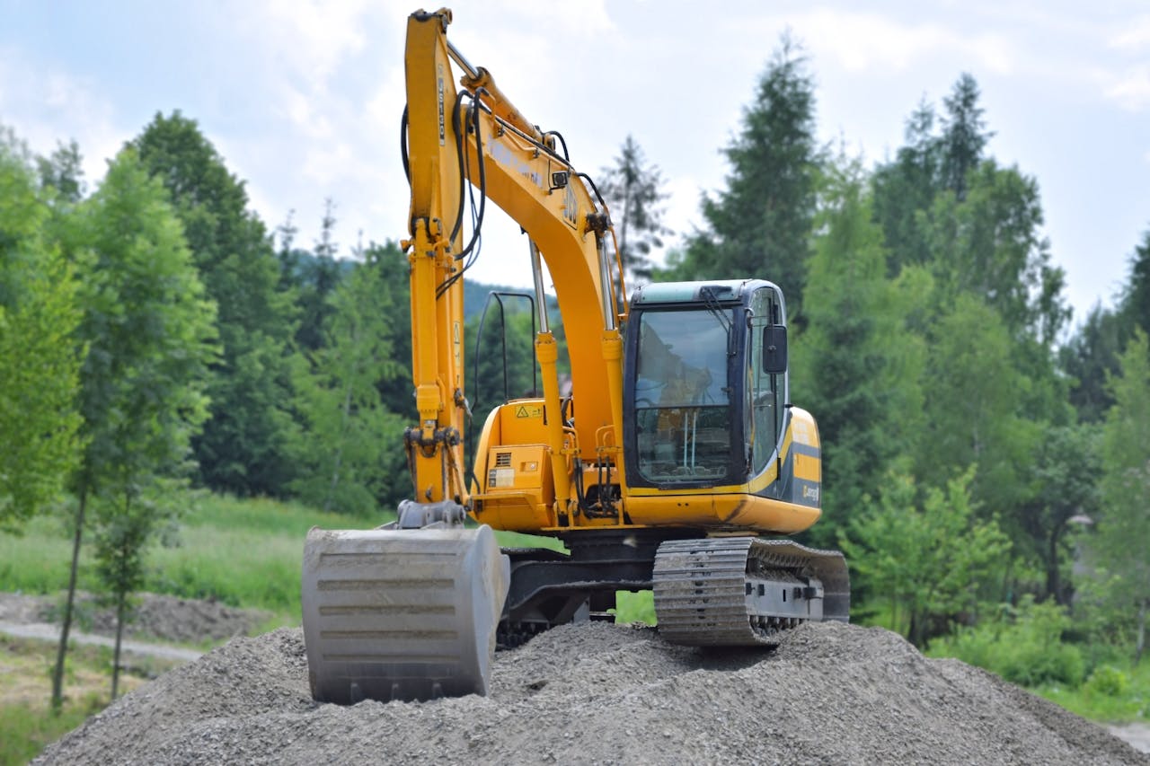 gallery-03 A yellow excavator on a pile of gravel in a lush, green forest setting in Poland.